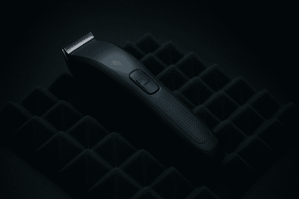 Cordless hair clipper with insulated shell and rubber elements on a sound-absorbing mat, under low-key lighting.