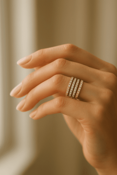 Hand modeling a stack of slim eternity and Pavé rings in mixed metals with sparkling diamonds.