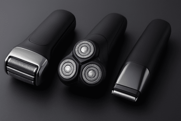 Three types of men's electric razors foil, rotary, and blade displayed on a dark matte surface, highlighting head details.