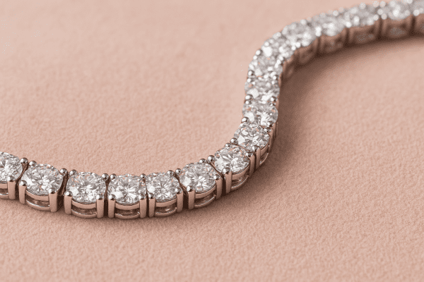 Macro view of a tennis bracelet on blush suede, highlighting diamond precision and setting details.