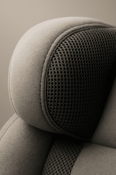 Macro of a car seat's plush headrest and reinforced stitching with breathable fabric.